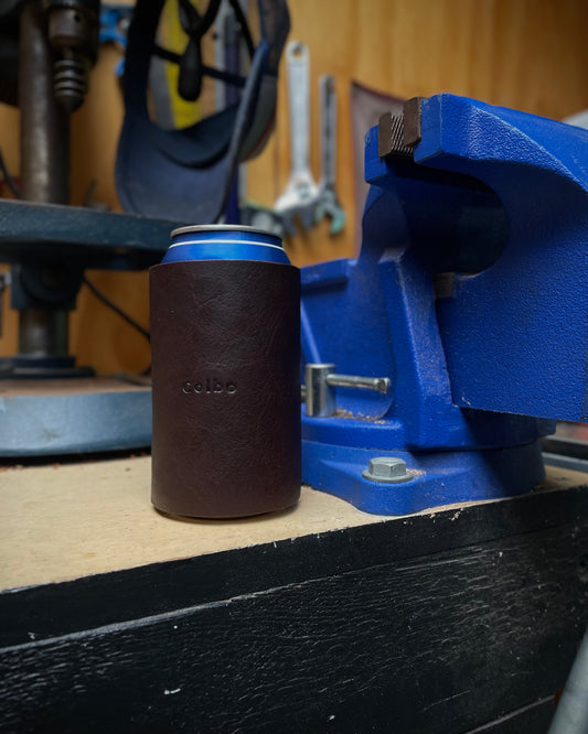 Can with a brown leather sleeve on a blue vise in a workshop setting