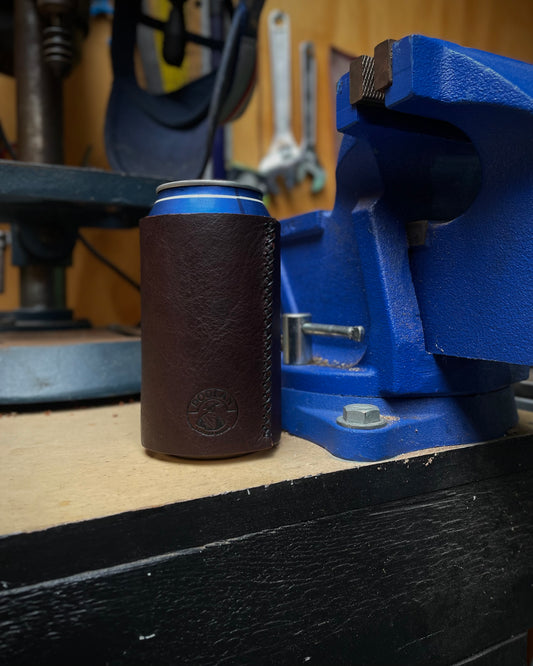 Brown leather can holder with blue rim on a workbench with tools in the background