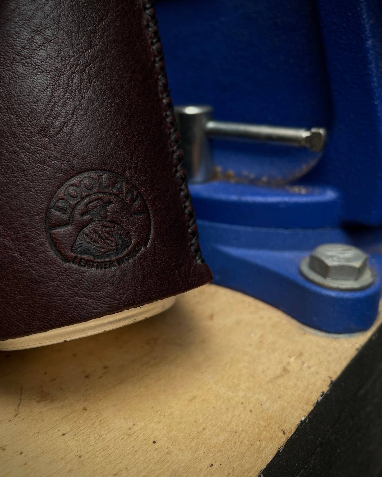Brown leather can holder with a brand logo on a blue background