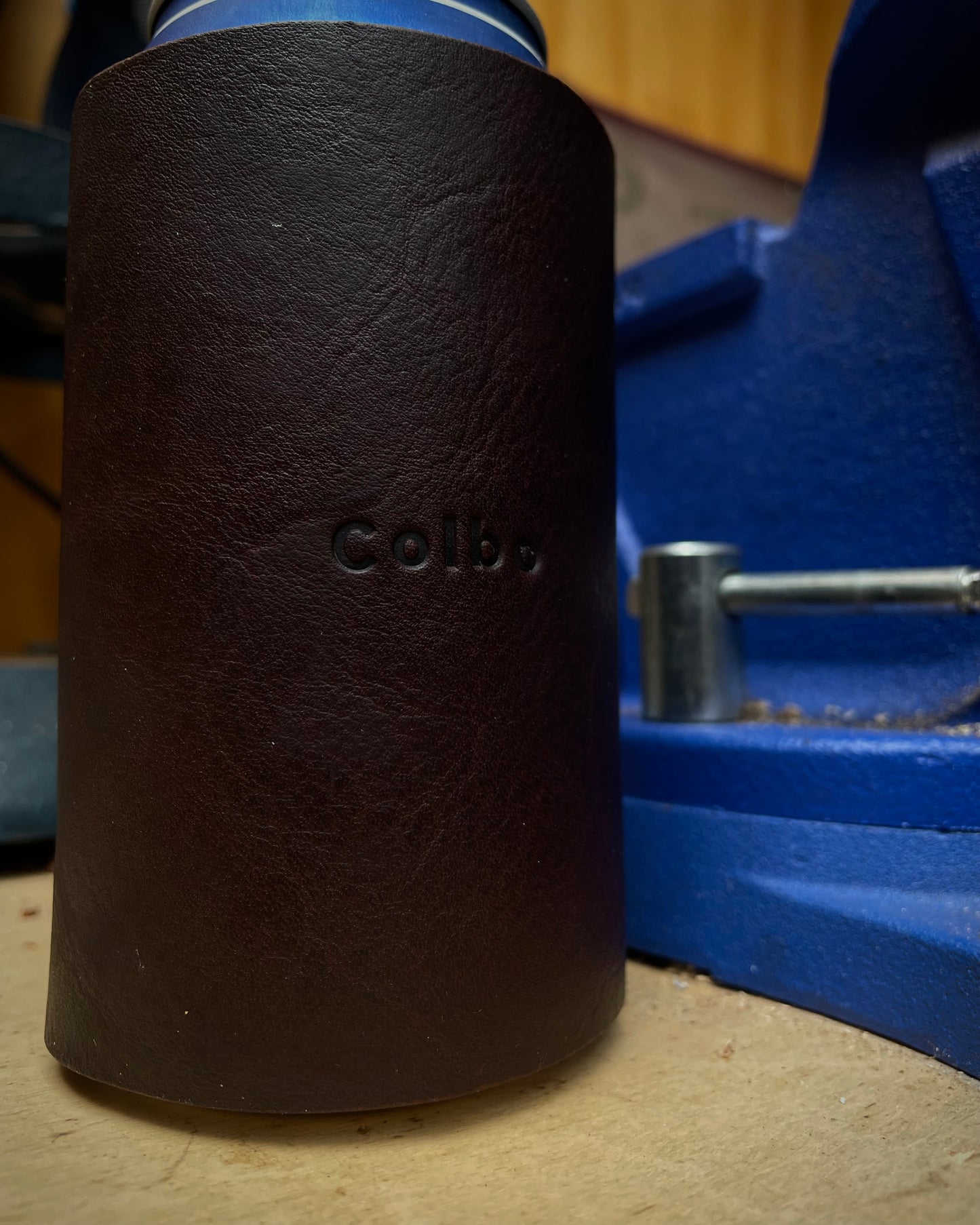 Brown leather can holder with custom branding on a blue background