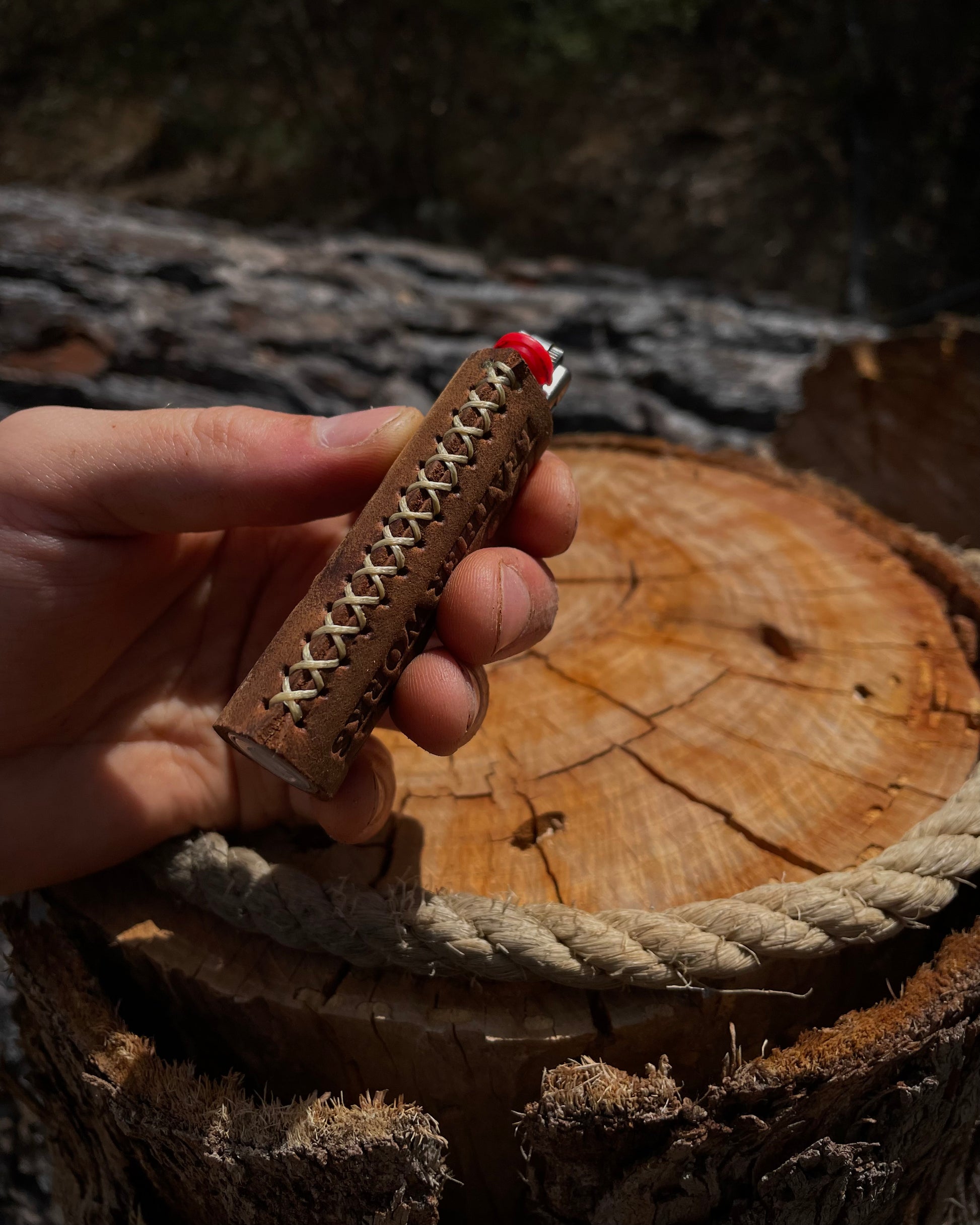 Hand holding a wooden lighter with rope design against a natural background