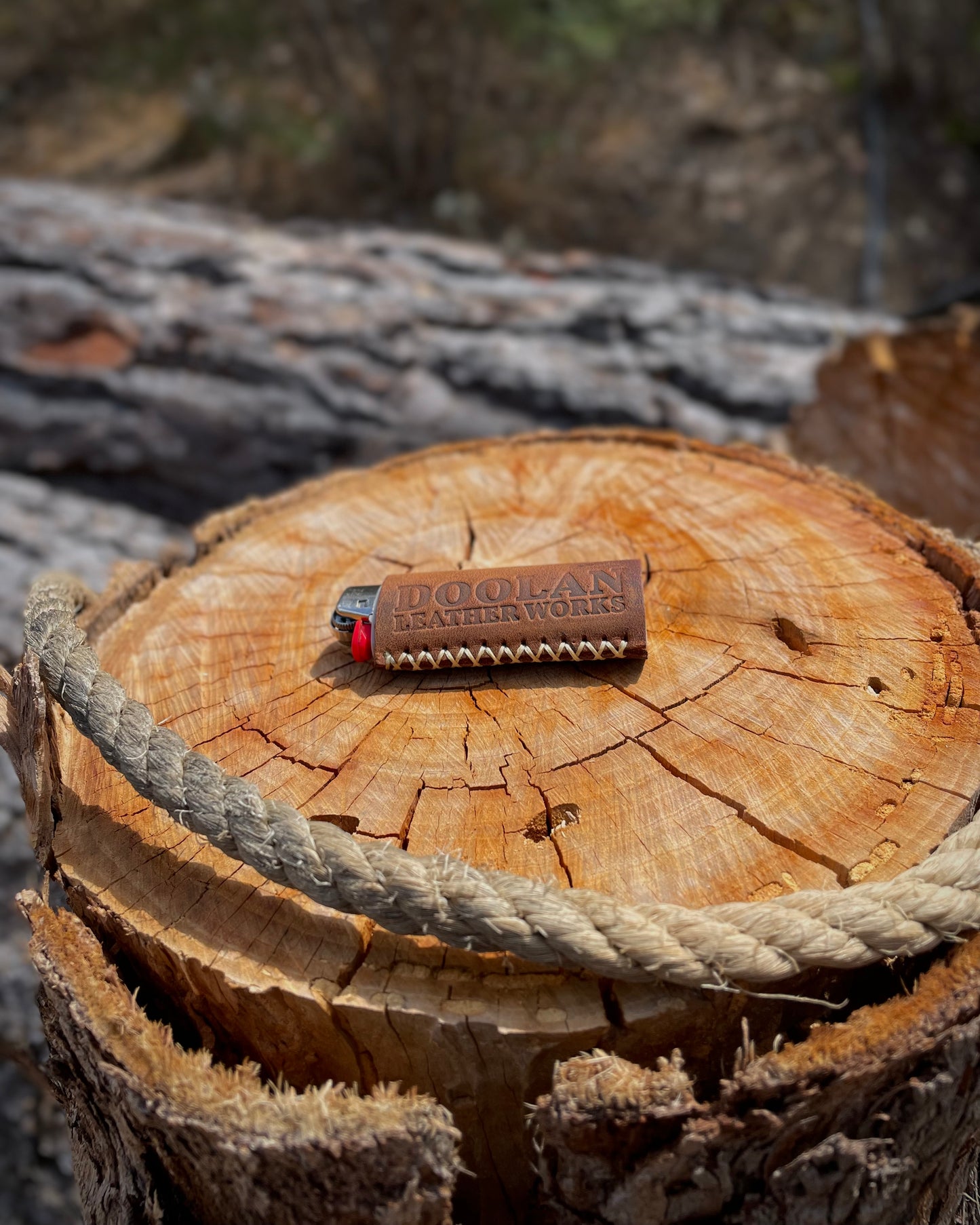 Lighter on a wooden log with a rope, surrounded by natural elements