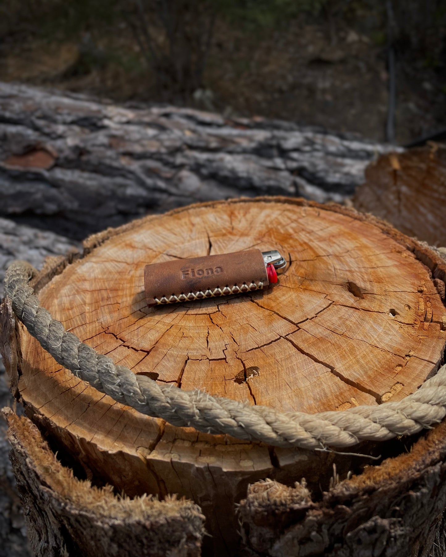 Lighter with leather cover on a wooden log