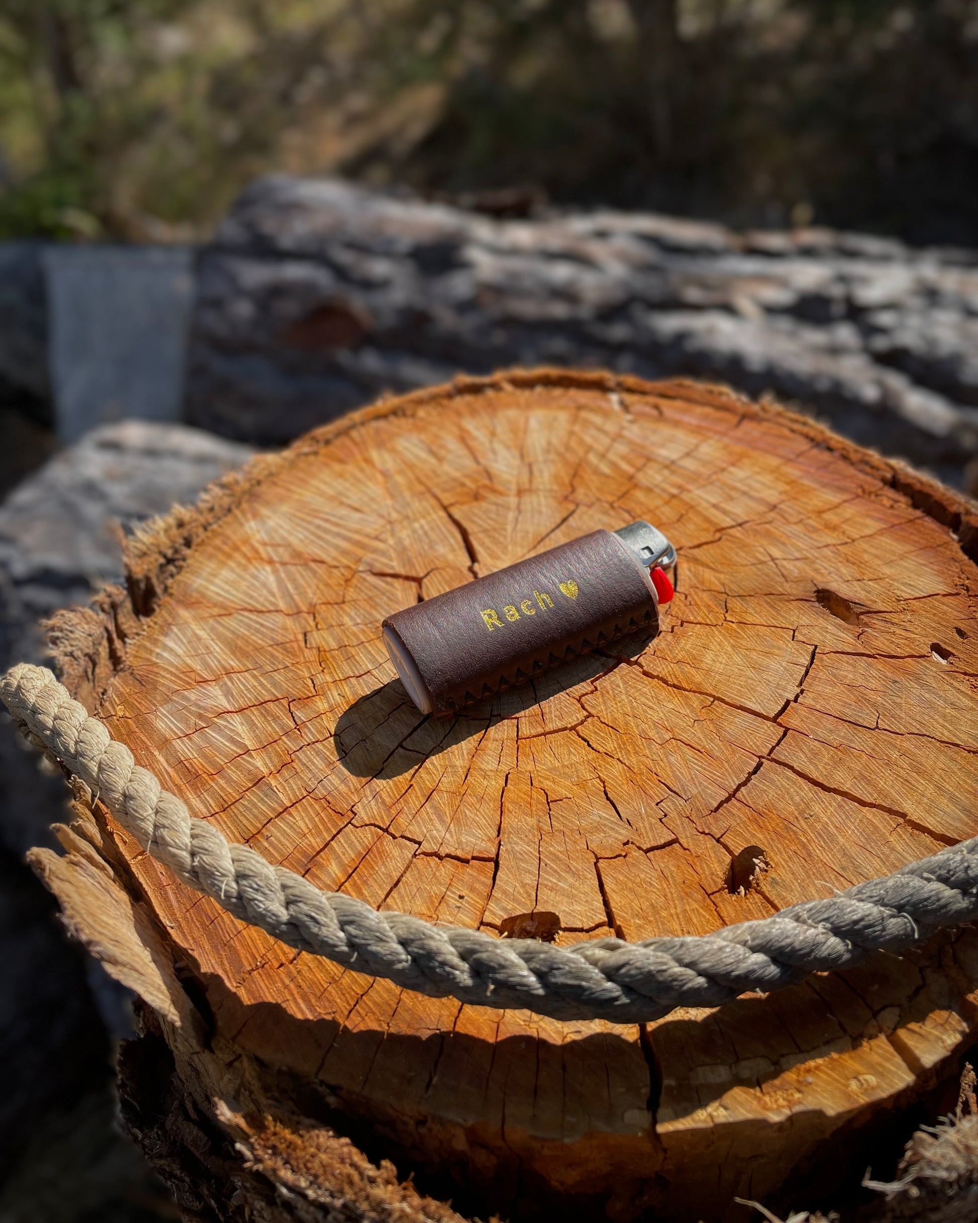 Leather lighter case on a wooden log with a rope, outdoors